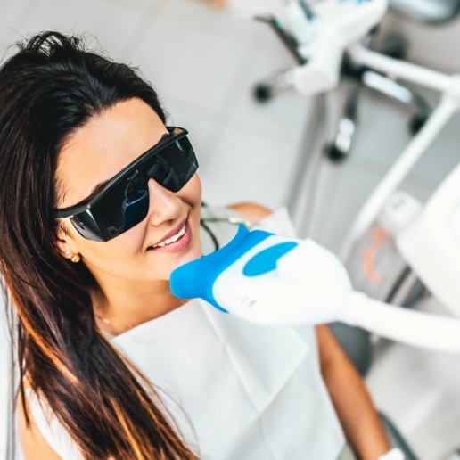 Young woman getting teeth whitening in dental office