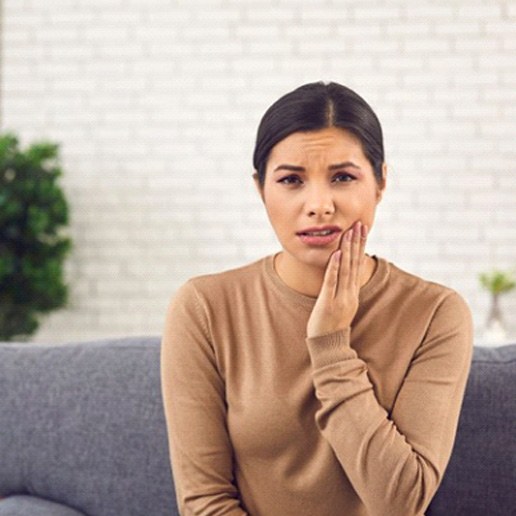 a woman touching her cheek due to tooth pain